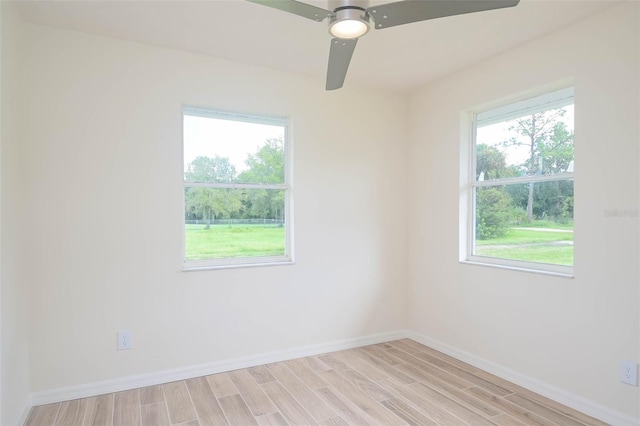 spare room featuring baseboards, a wealth of natural light, and light wood-style floors