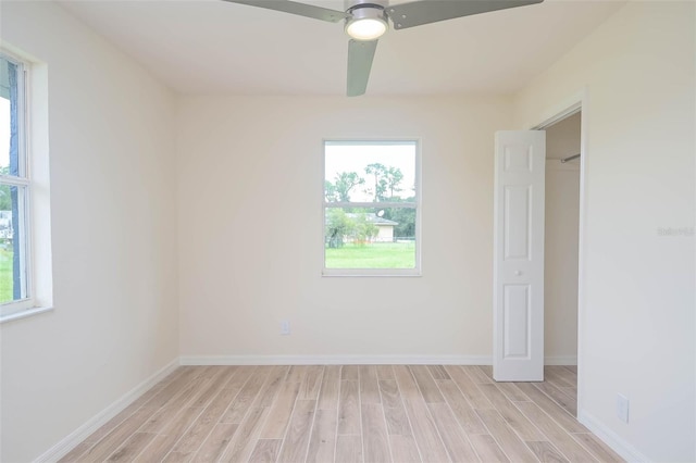 unfurnished bedroom with multiple windows, light wood-style flooring, and baseboards