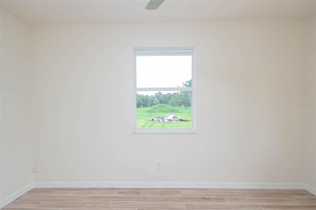 unfurnished room with a ceiling fan, wood finish floors, and baseboards