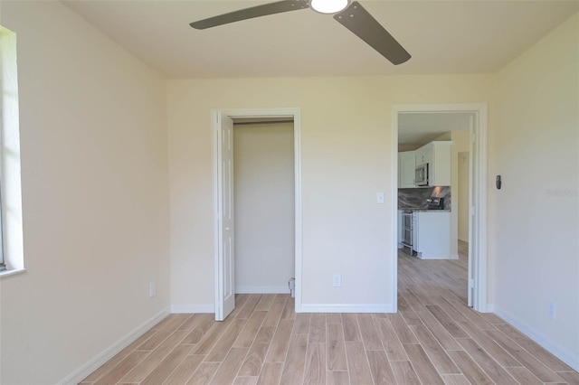 unfurnished bedroom featuring light wood-style floors, a ceiling fan, baseboards, and a closet