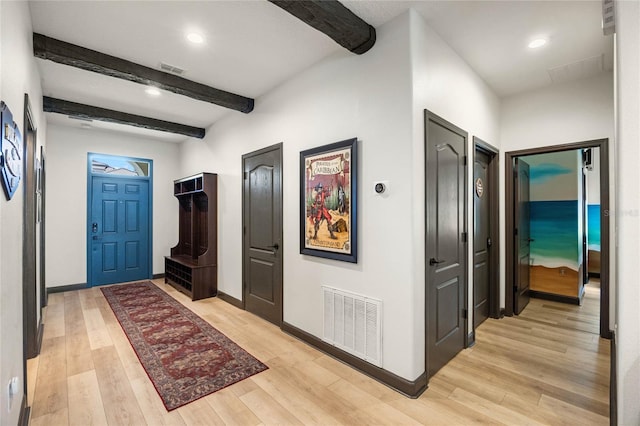 entryway with light wood-style floors, baseboards, visible vents, and beamed ceiling