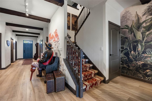 stairway featuring baseboards, beamed ceiling, and hardwood / wood-style floors