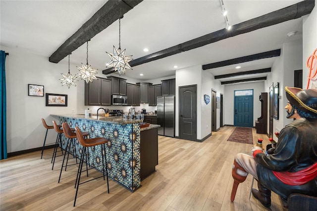 kitchen featuring appliances with stainless steel finishes, a peninsula, a breakfast bar area, and light wood finished floors