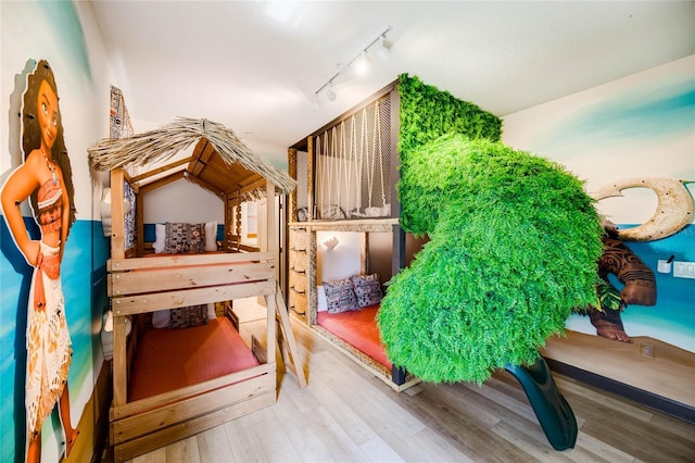 bedroom featuring wood finished floors and rail lighting