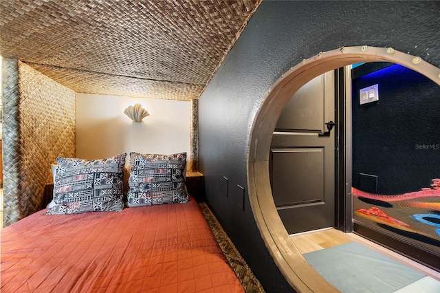 bedroom with brick ceiling, vaulted ceiling, a textured wall, and arched walkways