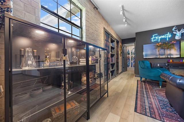 wine cellar featuring wood-type flooring, rail lighting, a textured ceiling, and a towering ceiling