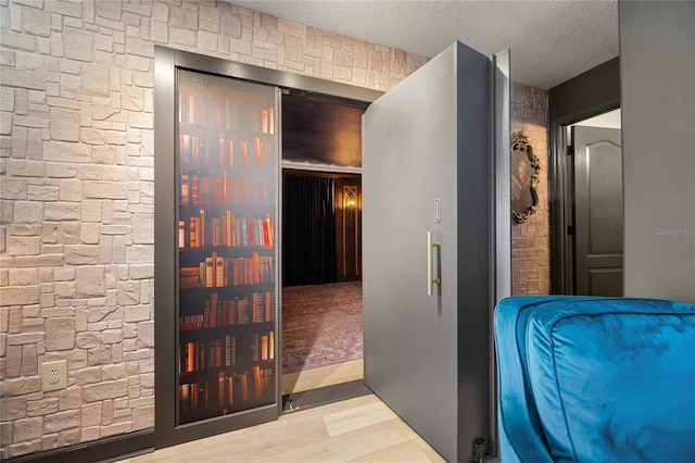 corridor with a textured ceiling and wood finished floors