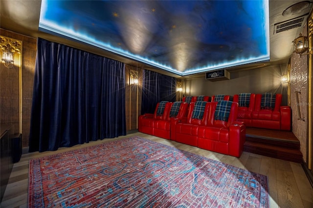 home theater with visible vents, a tray ceiling, and hardwood / wood-style floors