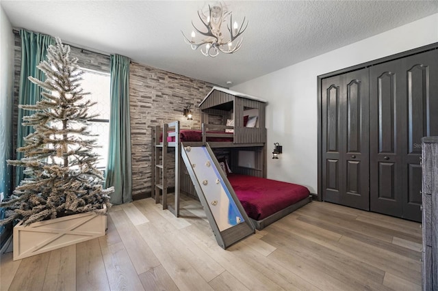 unfurnished bedroom featuring a textured ceiling, a closet, wood-type flooring, and a chandelier