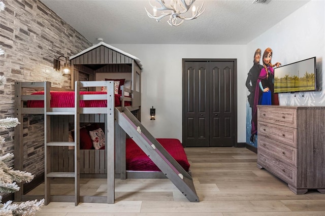 bedroom with a notable chandelier, a textured ceiling, a closet, and wood finished floors