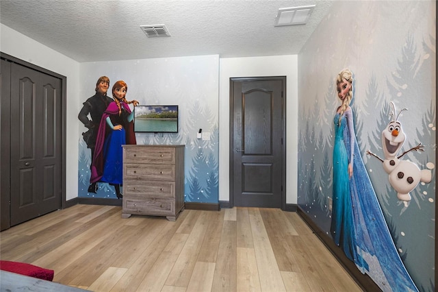 foyer entrance featuring wood-type flooring, visible vents, and a textured ceiling