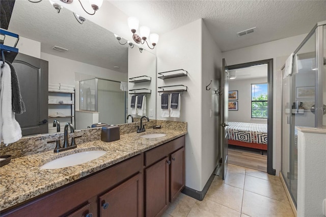 ensuite bathroom featuring tile patterned flooring, visible vents, a sink, and a shower stall