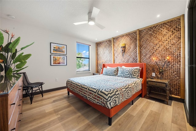 bedroom featuring light wood-style floors, a textured ceiling, baseboards, and a ceiling fan