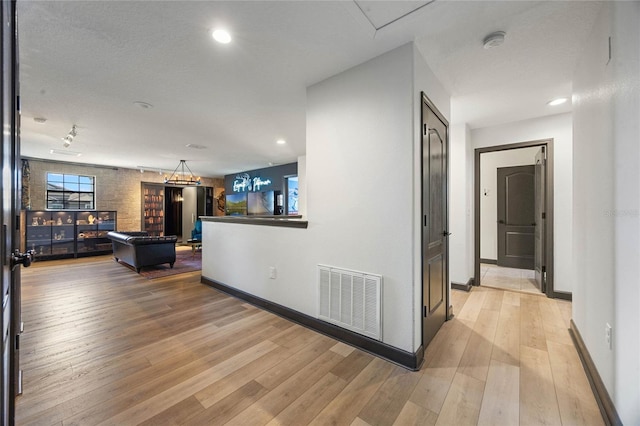 corridor featuring baseboards, visible vents, and light wood-style floors