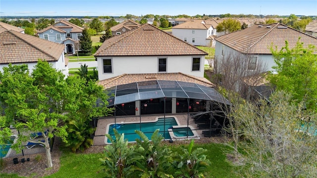 back of house featuring a tile roof, a residential view, a pool with connected hot tub, and a patio