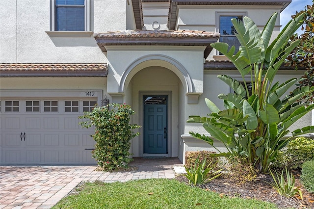 doorway to property with a tile roof, decorative driveway, and stucco siding