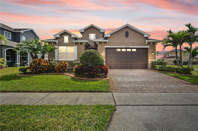 view of front of house with a front lawn, decorative driveway, a garage, and stucco siding