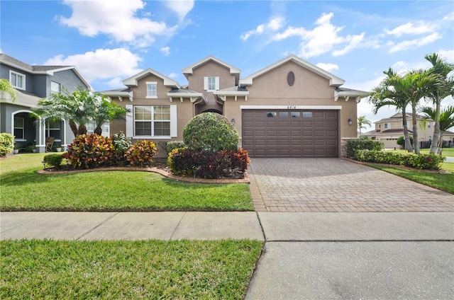 view of front of home featuring stucco siding, a front lawn, decorative driveway, and a garage