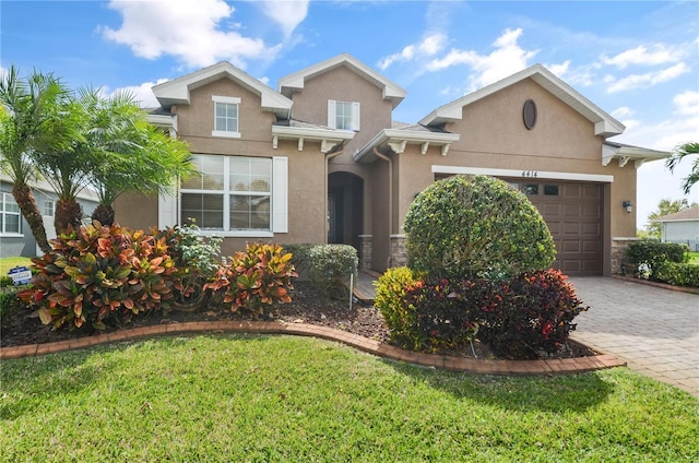 traditional home featuring stucco siding, decorative driveway, and a garage