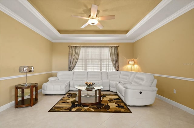 tiled living room featuring ornamental molding, baseboards, a tray ceiling, and a ceiling fan