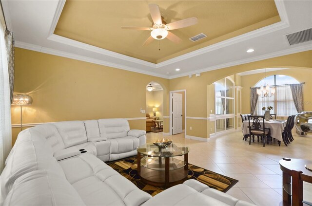 living room with a tray ceiling, arched walkways, and visible vents