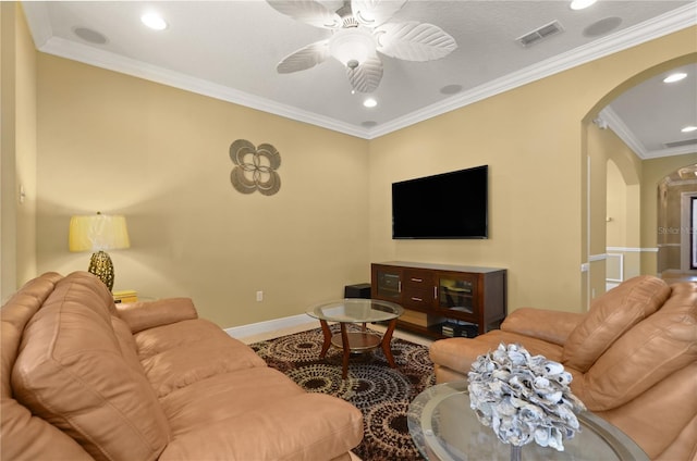 living area with visible vents, ornamental molding, a ceiling fan, arched walkways, and baseboards