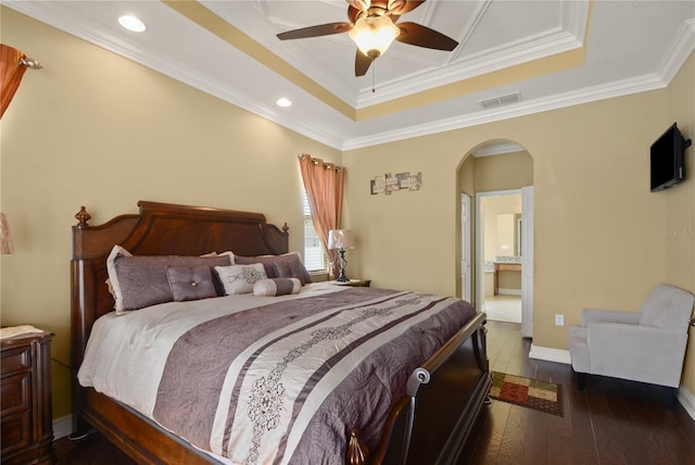 bedroom with dark wood finished floors, a tray ceiling, arched walkways, and visible vents