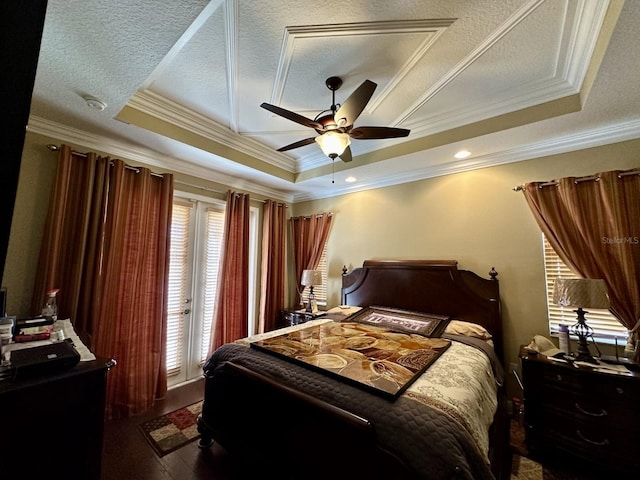 bedroom with wood finished floors, a textured ceiling, a raised ceiling, and access to outside