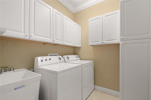 washroom featuring crown molding, baseboards, washing machine and dryer, cabinet space, and a sink