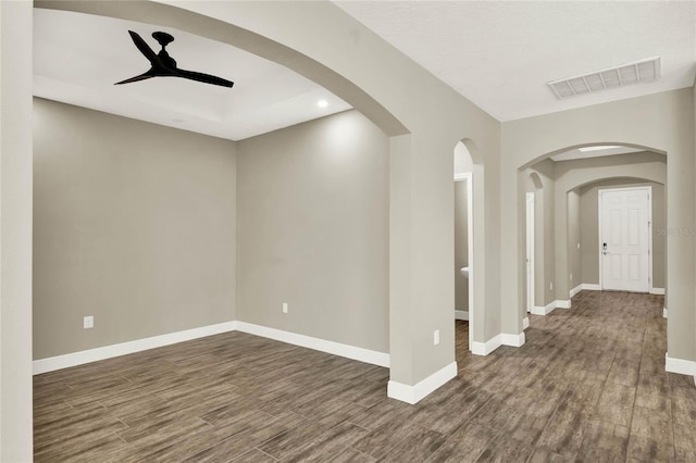 empty room featuring visible vents, ceiling fan, baseboards, and wood finished floors