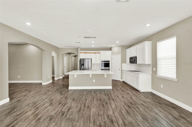 kitchen with an island with sink, dark wood-style flooring, decorative backsplash, stainless steel refrigerator with ice dispenser, and open floor plan