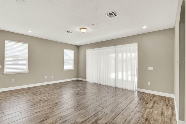 spare room with visible vents, baseboards, and wood finished floors