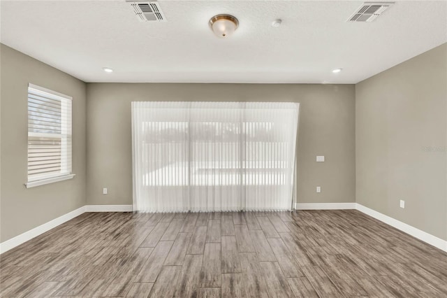 unfurnished room featuring wood finished floors, visible vents, and baseboards