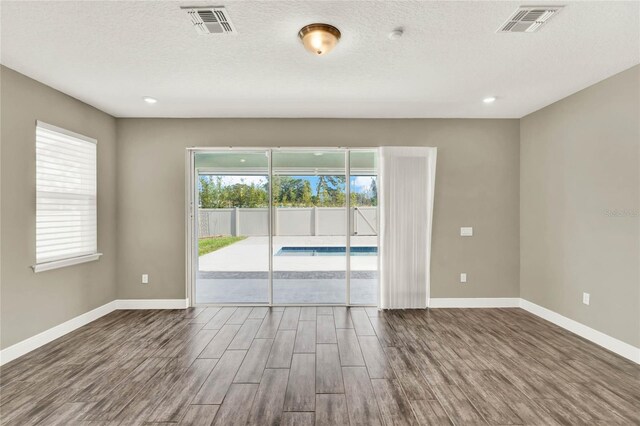 empty room with visible vents, baseboards, and wood finished floors