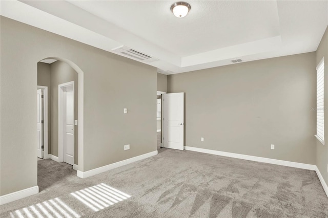 carpeted empty room with arched walkways, visible vents, and baseboards