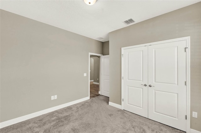 unfurnished bedroom featuring baseboards, visible vents, a closet, and light carpet