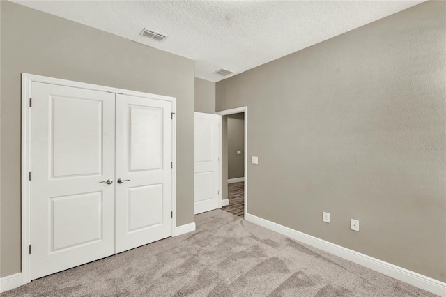 unfurnished bedroom featuring light carpet, visible vents, a closet, and baseboards