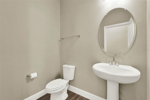 bathroom with baseboards, toilet, and wood finished floors