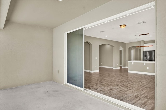 unfurnished room with visible vents, arched walkways, baseboards, and wood finished floors