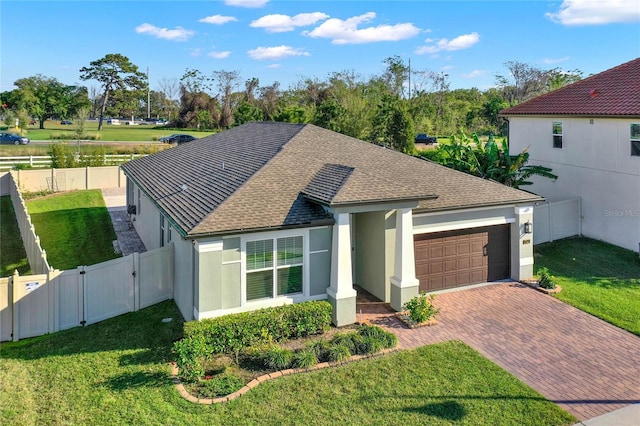 view of front facade featuring stucco siding, decorative driveway, a fenced backyard, an attached garage, and a gate