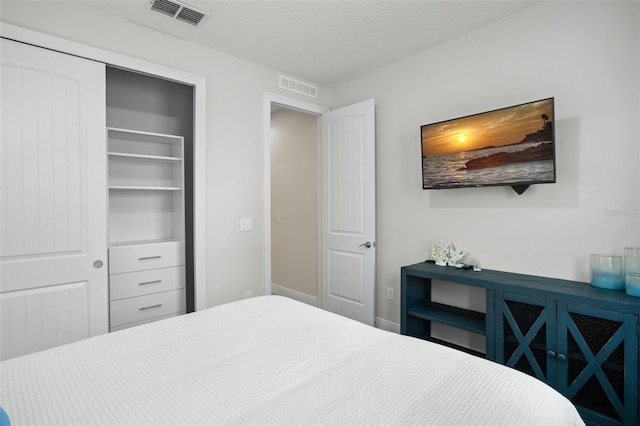 bedroom with baseboards, a textured ceiling, visible vents, and a closet