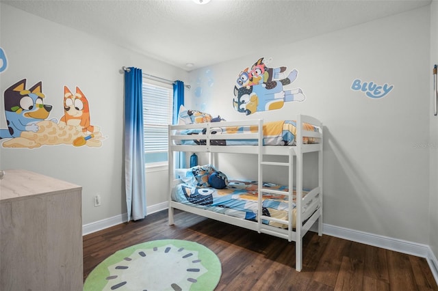 bedroom featuring a textured ceiling, baseboards, and wood finished floors