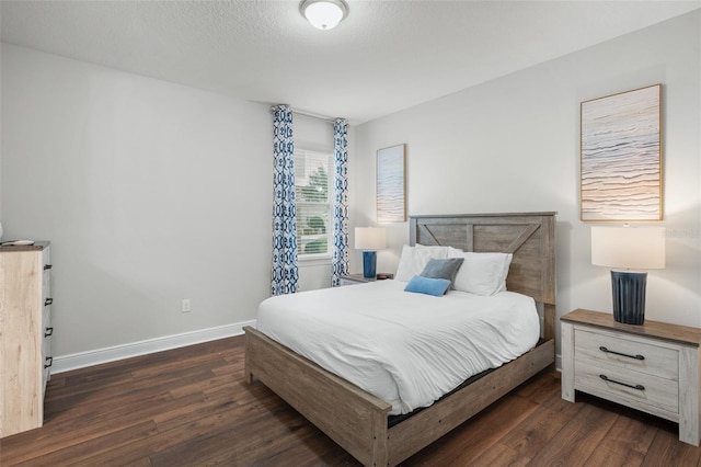 bedroom with dark wood-style floors, baseboards, and a textured ceiling