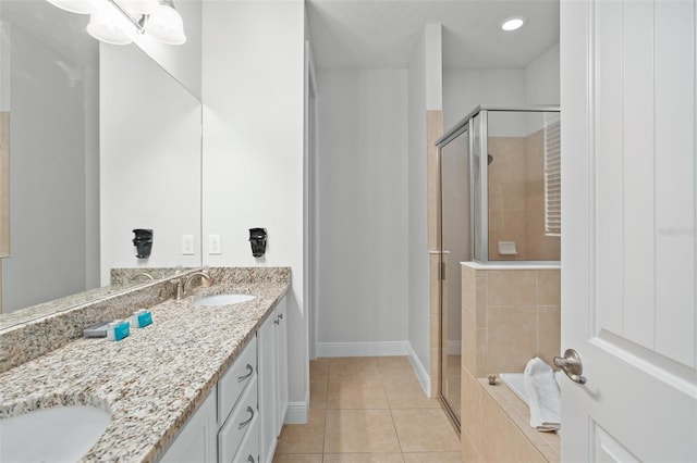 bathroom featuring double vanity, a stall shower, a sink, tile patterned flooring, and baseboards