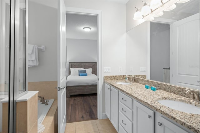 ensuite bathroom featuring double vanity, tile patterned flooring, a sink, and a bath