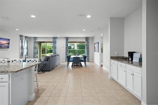 kitchen featuring recessed lighting, light tile patterned flooring, a kitchen bar, and white cabinets