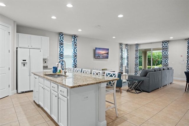kitchen featuring a breakfast bar area, light tile patterned flooring, white appliances, a sink, and open floor plan