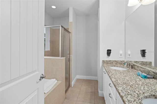 bathroom featuring tile patterned flooring, vanity, baseboards, a bath, and a stall shower