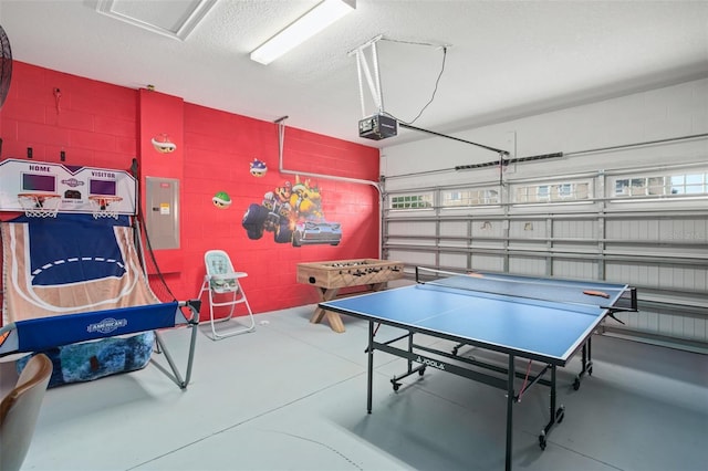 rec room with concrete block wall, finished concrete flooring, a textured ceiling, a garage, and electric panel