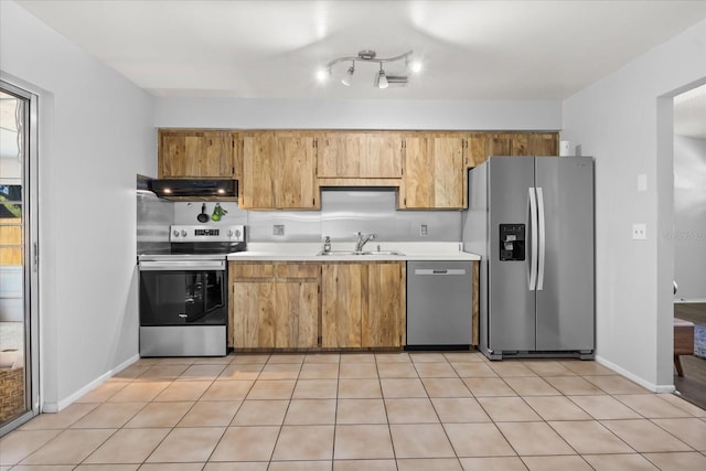 kitchen with under cabinet range hood, light countertops, light tile patterned floors, appliances with stainless steel finishes, and a sink